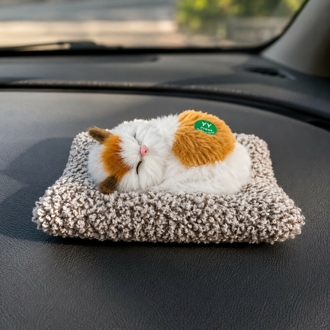 Sleeping cat plush toy with soft cushion on car dashboard