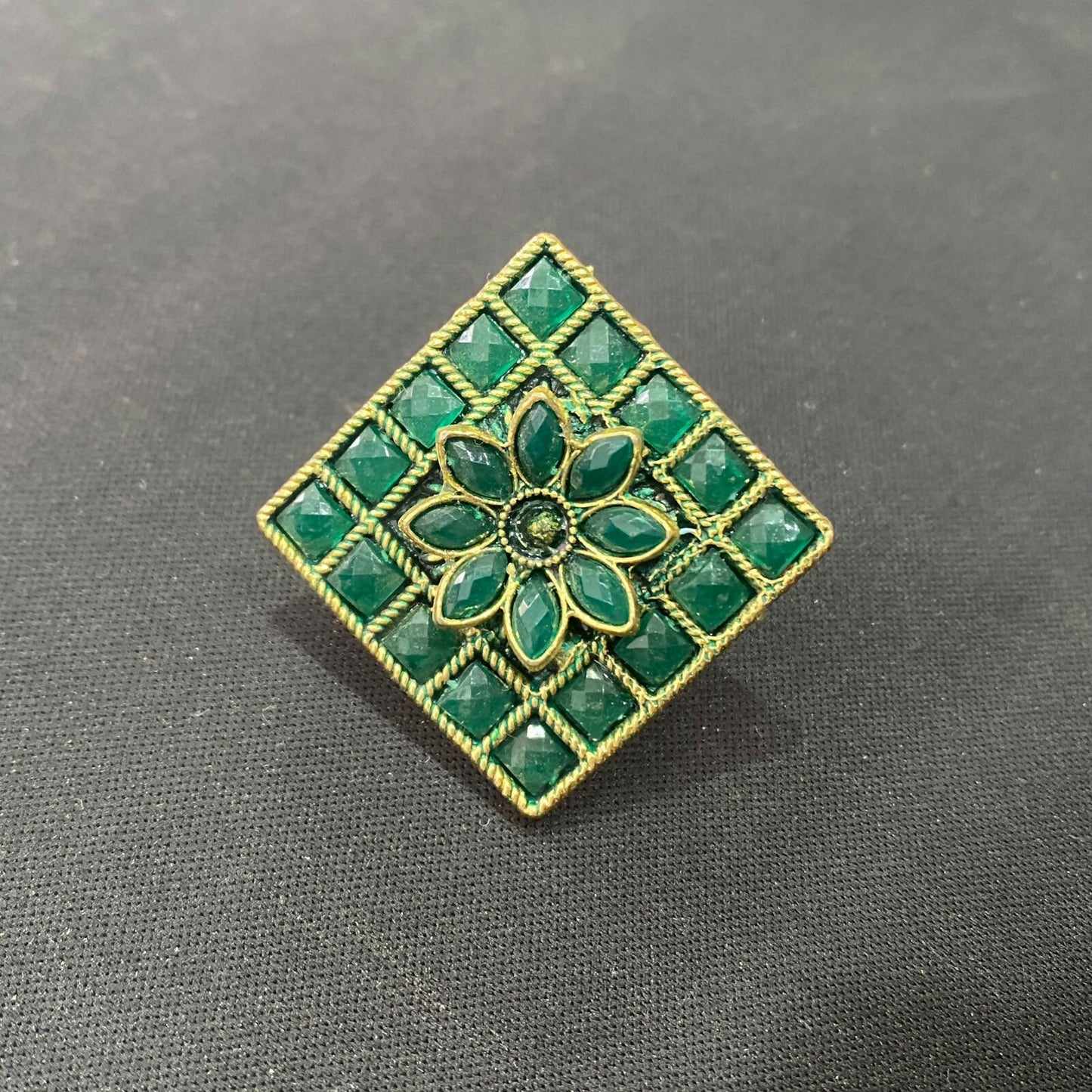 Vintage green floral statement ring sparkling on a neutral background