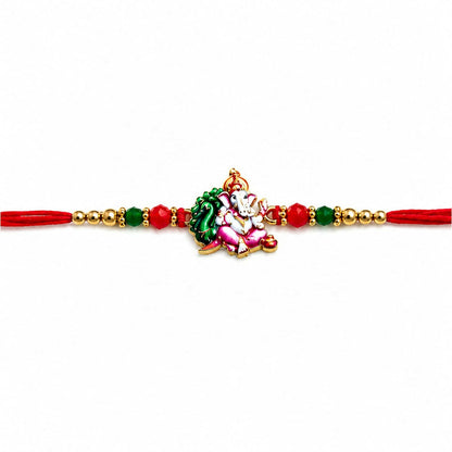 A red thread with an enamel Ganesha charm, green and red crystal beads, and golden beads, centered on a plain white