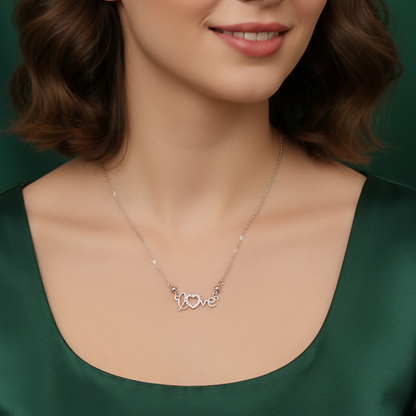 Close-up of silver heart pendant encrusted with sparkling crystals and love script