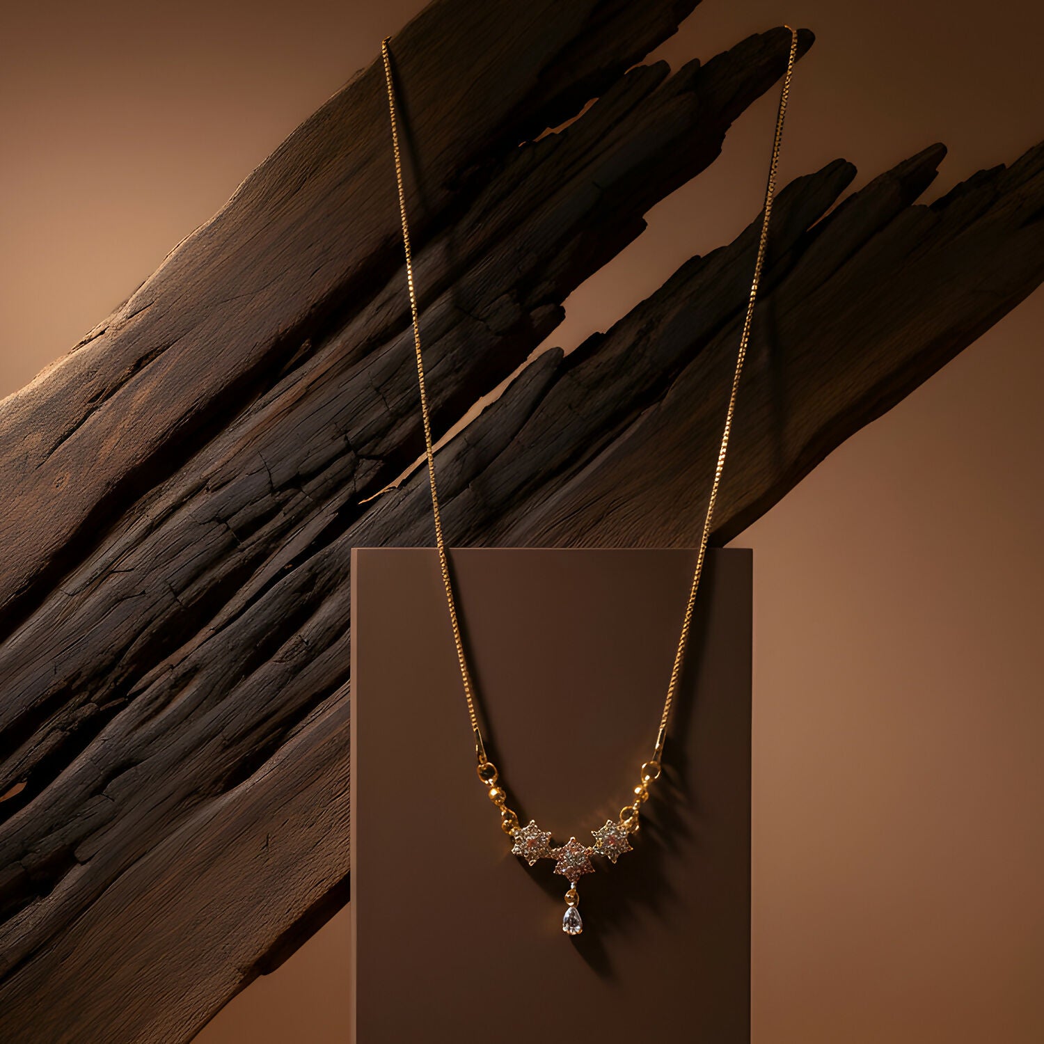Front view of gold finish necklace with floral stones and teardrop pendant