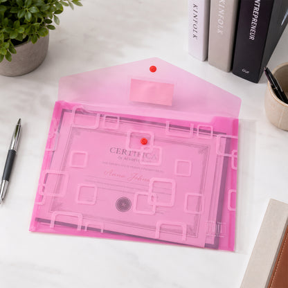 An open pink plastic document folder with a button closure, containing a certificate, on a white desk.