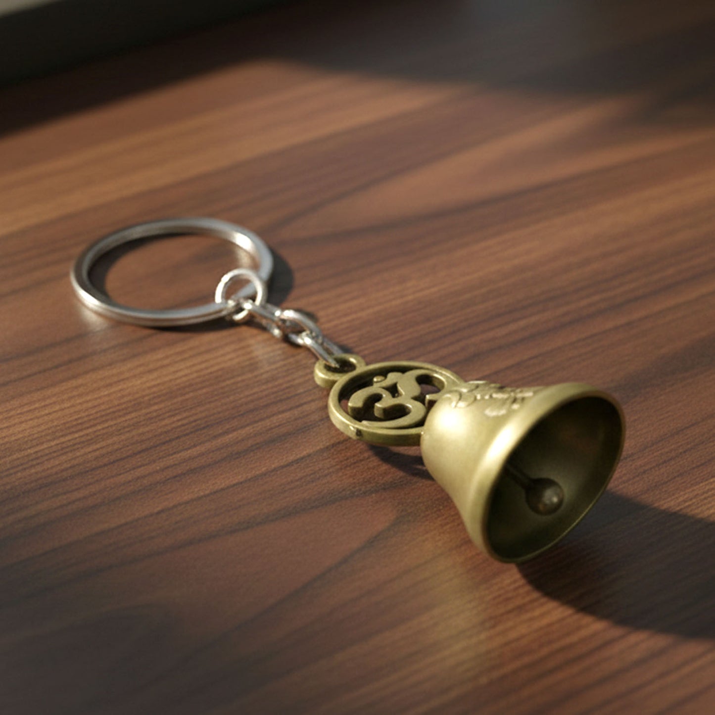 Om temple bell keychain held in hand, showing its compact size
