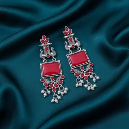Close-up of oxidized silver earrings showcasing traditional red stone design and pearl drops