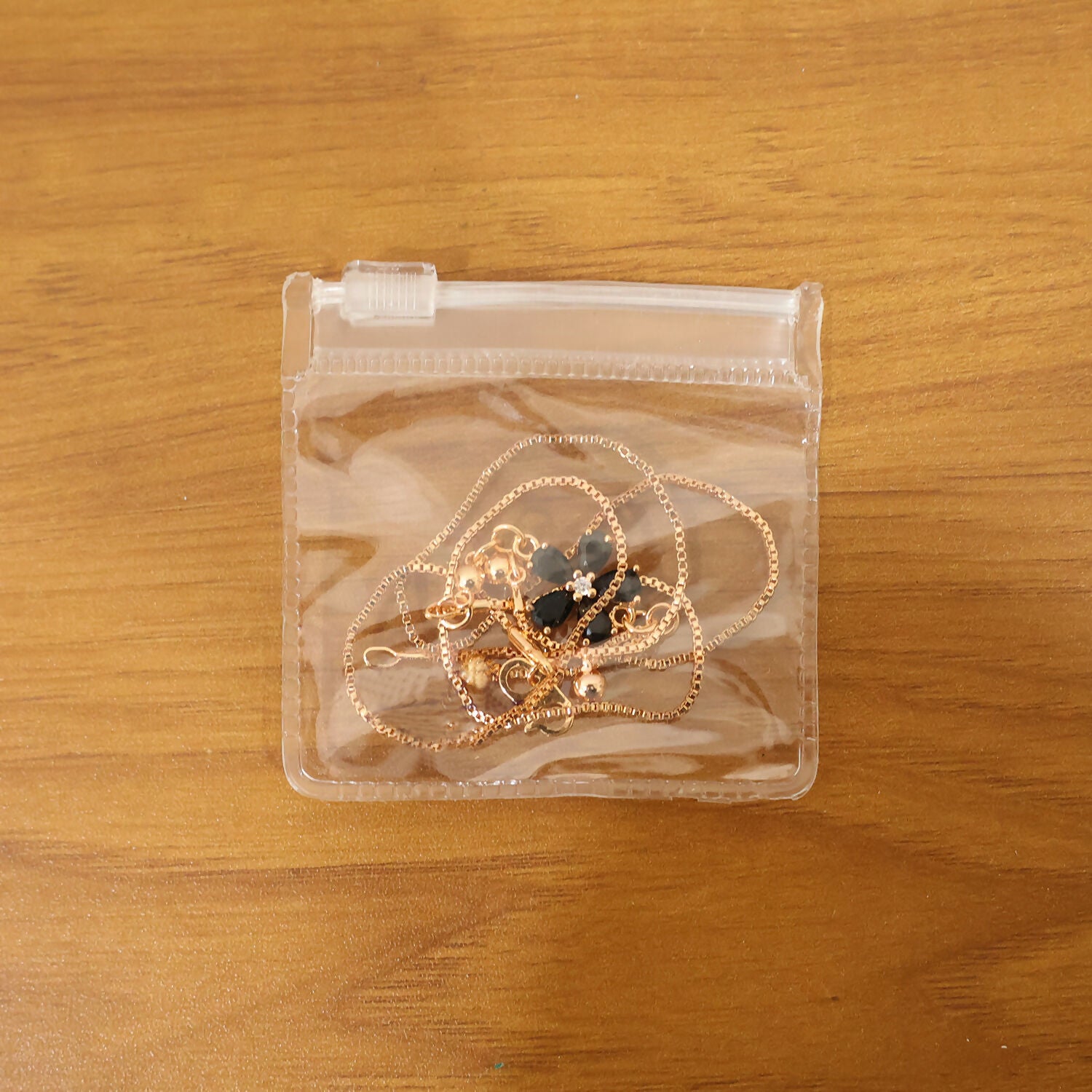 Full view of gold finish black floral pendant necklace laying flat