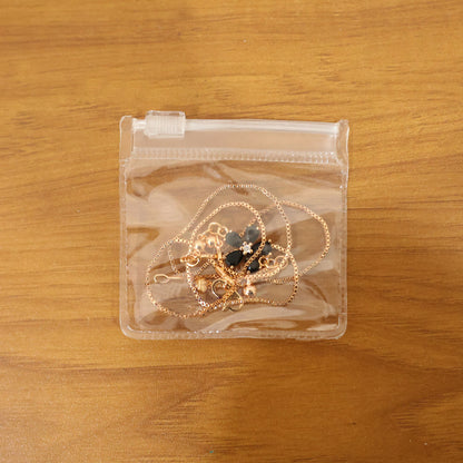 Full view of gold finish black floral pendant necklace laying flat