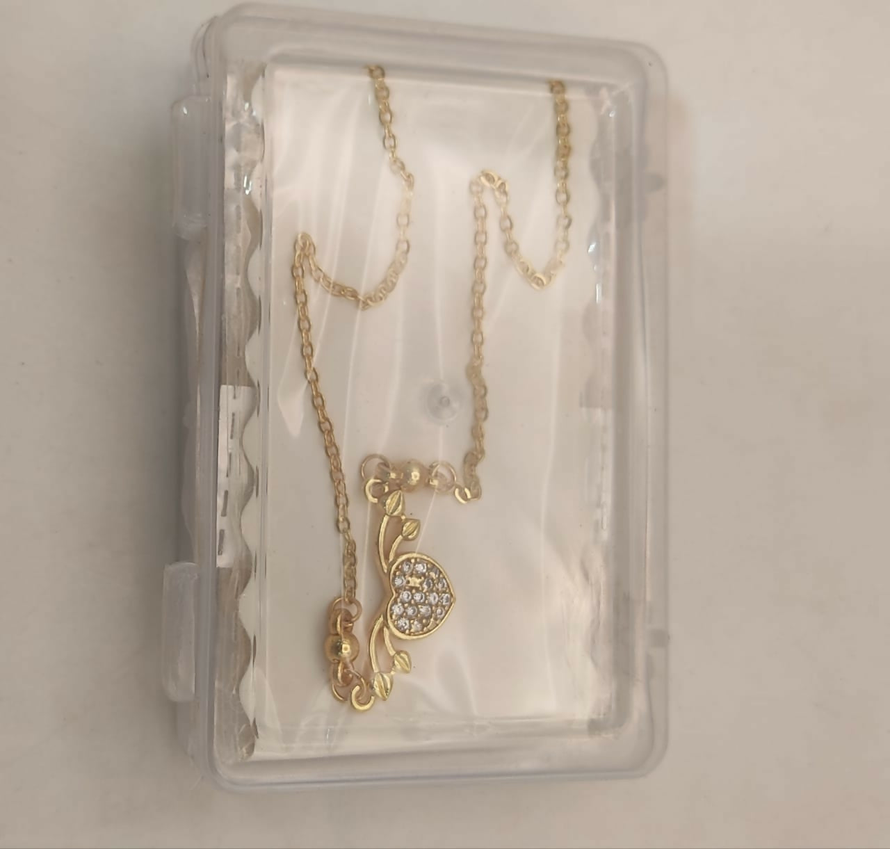 Gold heart necklace styled on model showing dainty and minimalist design
