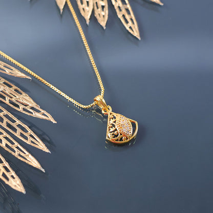 Close-up of gold plated pendant necklace cutwork and shimmering leaf detail