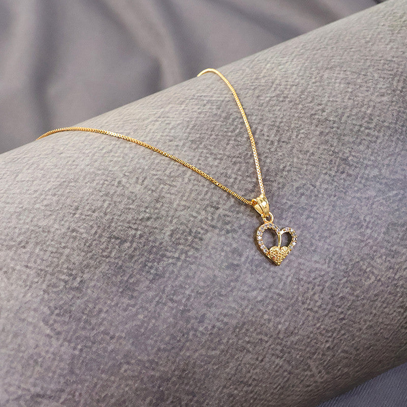 Close-up of gold-plated double heart pendant necklace showcasing textured inner heart and crystal accents
