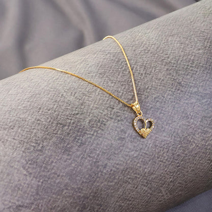 Close-up of gold-plated double heart pendant necklace showcasing textured inner heart and crystal accents