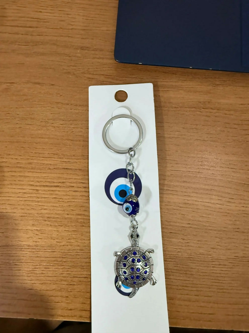 Turtle keychain with evil eye charm displayed on surface