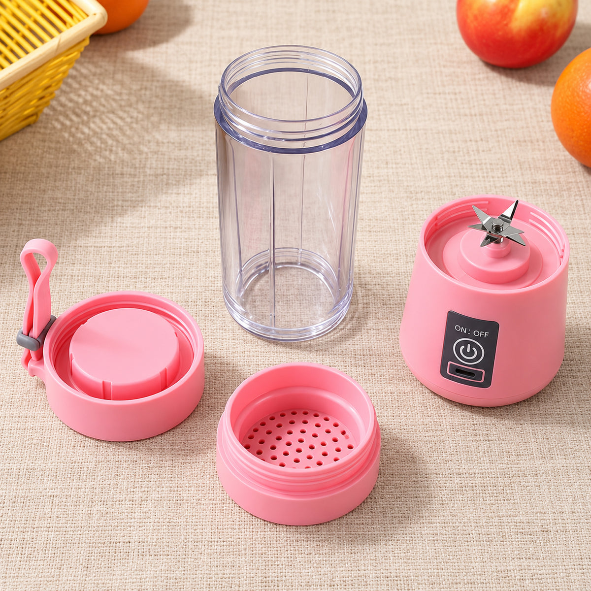 A disassembled pink portable blender with its base, clear jar, lid, and strainer laid out on a beige surface.