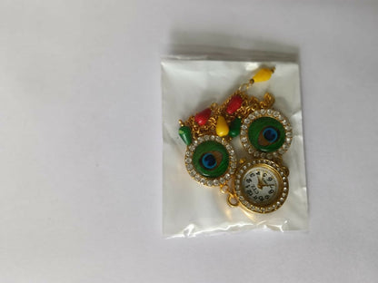A gold-tone bracelet watch with peacock eye designs, a central watch face, and colorful beads is sealed in a clear plastic
