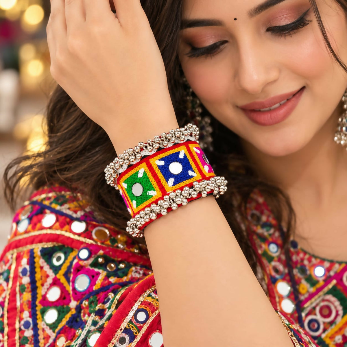 A woman wears a colorful embroidered kada bracelet with silver beads on her right wrist, smiling softly.
