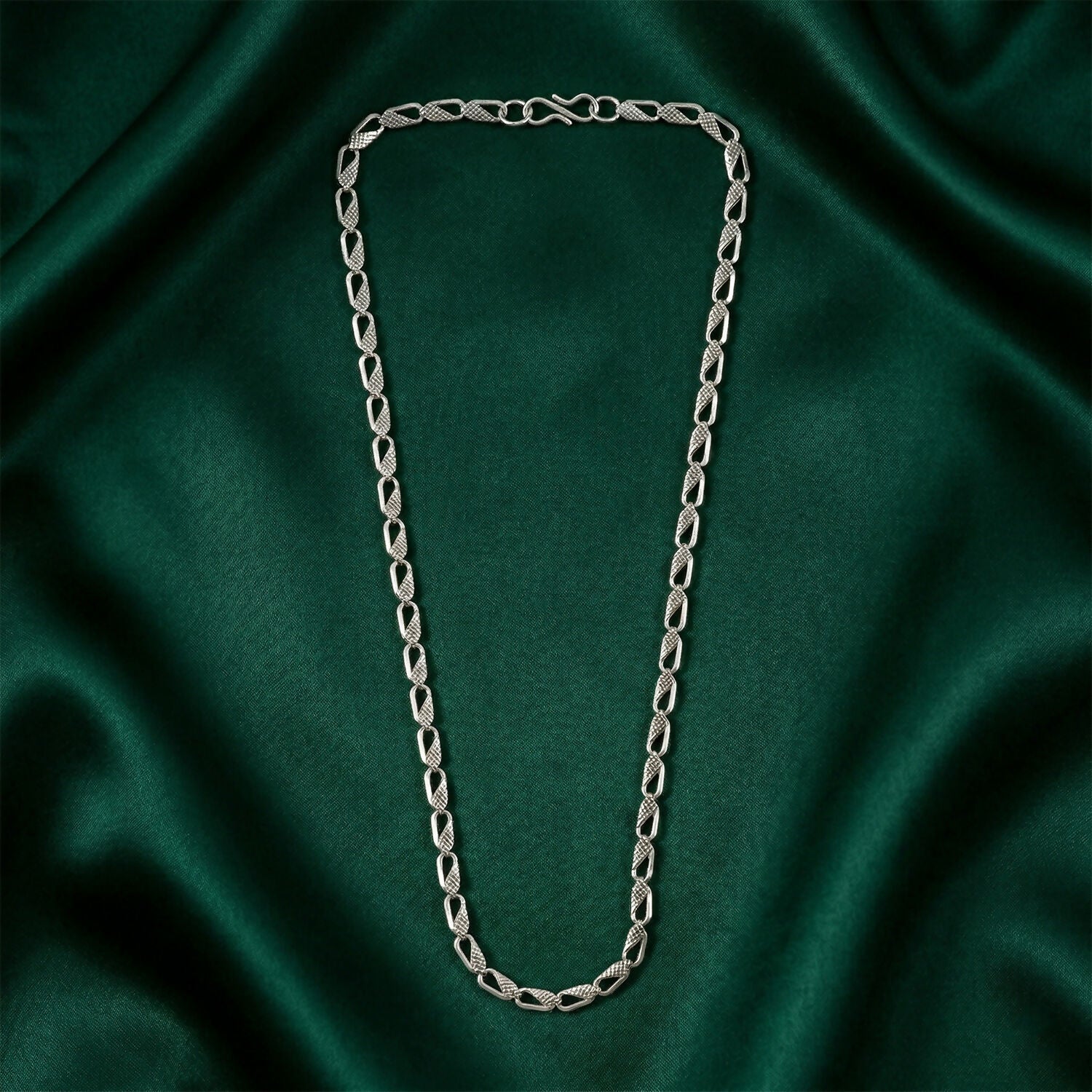 Silver designer chain necklace displayed on a dark background