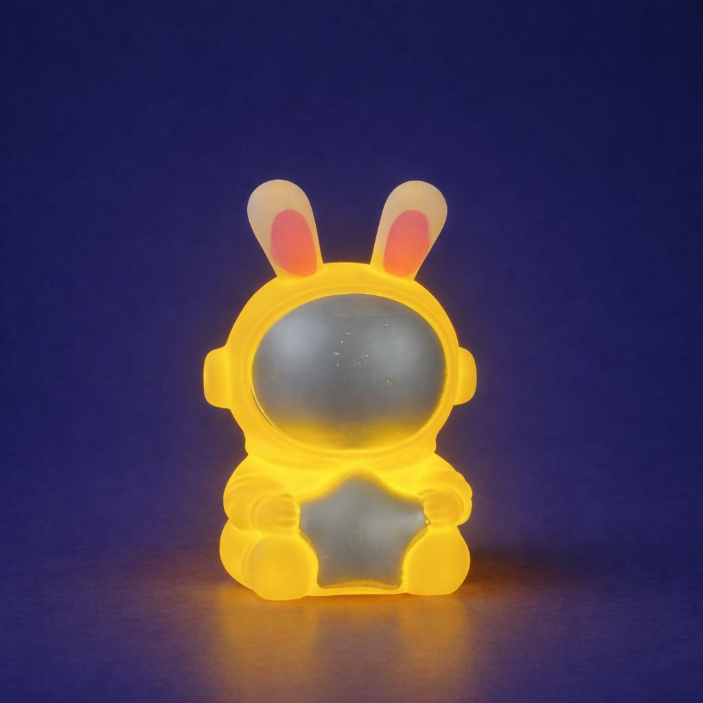 Close-up of cute bunny astronaut holding star LED night lamp