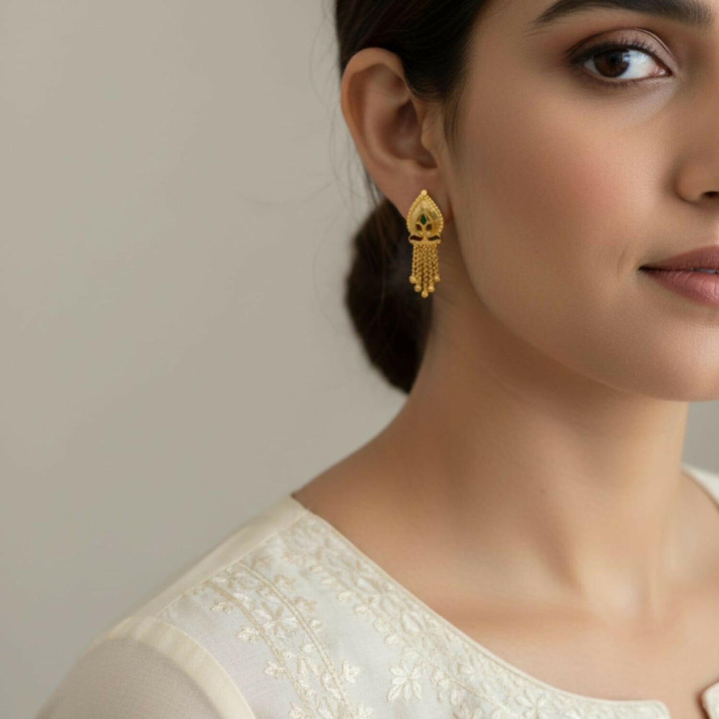Close-up of traditional gold-plated jhumka earrings with circular studs and dangling beads
