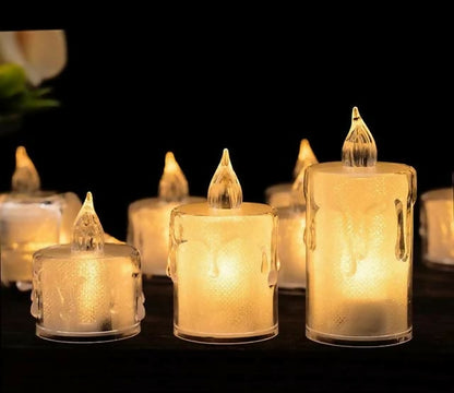 Several clear plastic LED candles, some lit, are arranged on a dark surface, creating a warm ambiance.