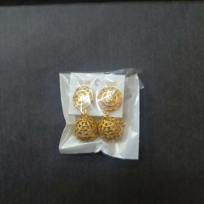 Gold tone jhumka earrings displayed on an earring holder