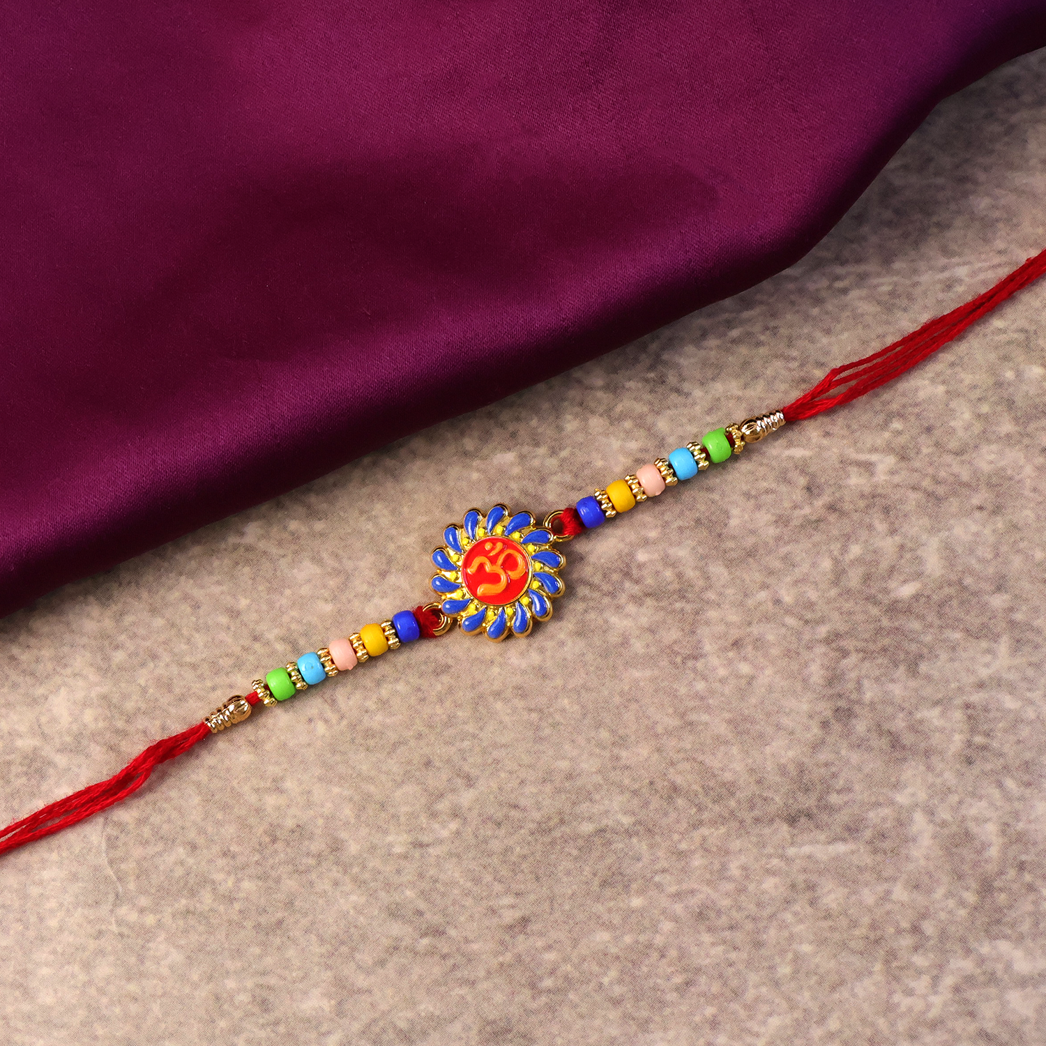 Side angle of Om Designer Rakhi emphasizing traditional thread and beads