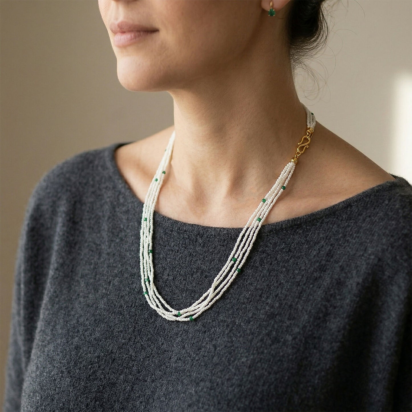 Close-up of white beads and green accents in layered mala