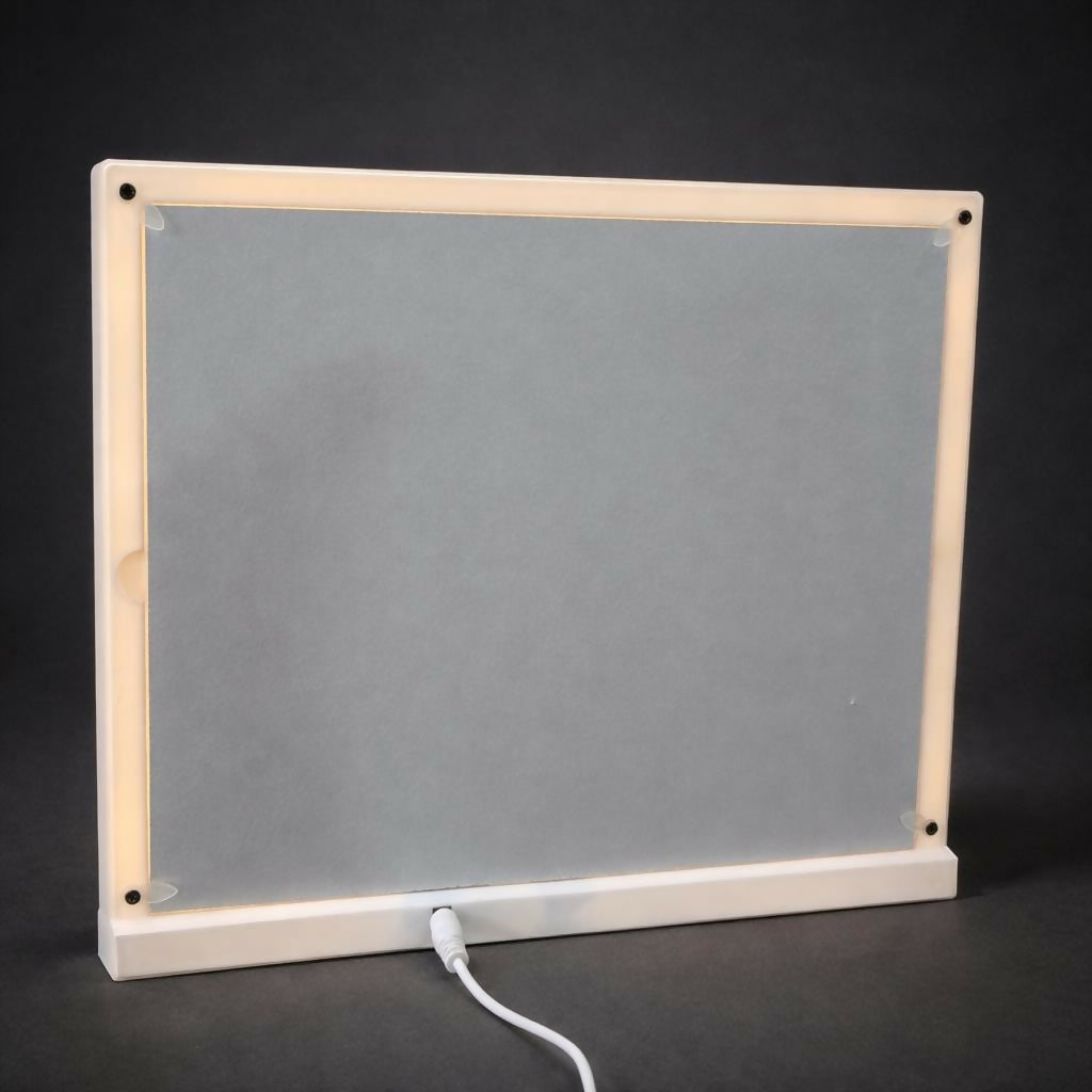 Decorative white photo frame collage lit with warm LEDs on tabletop