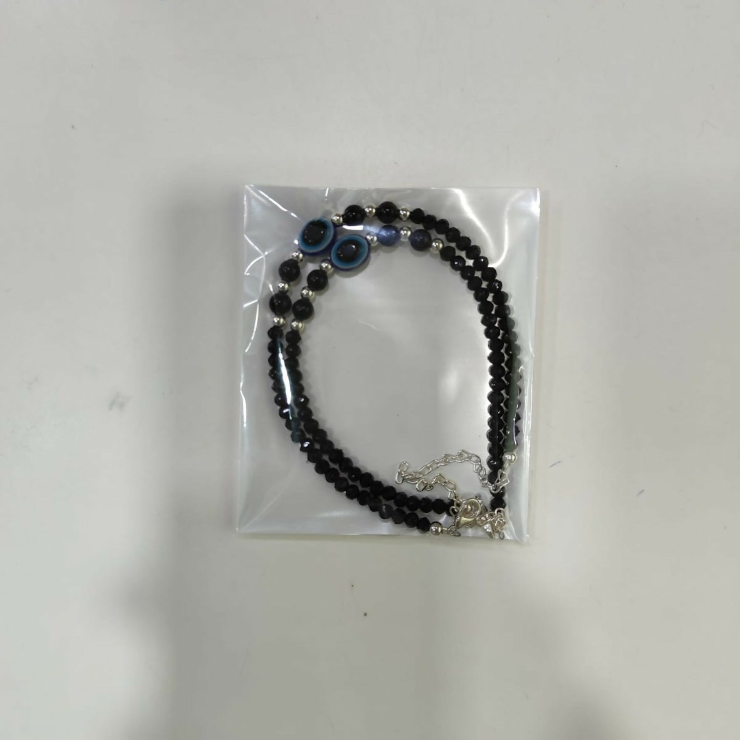 Lifestyle shot of the black evil eye anklet pair for women.