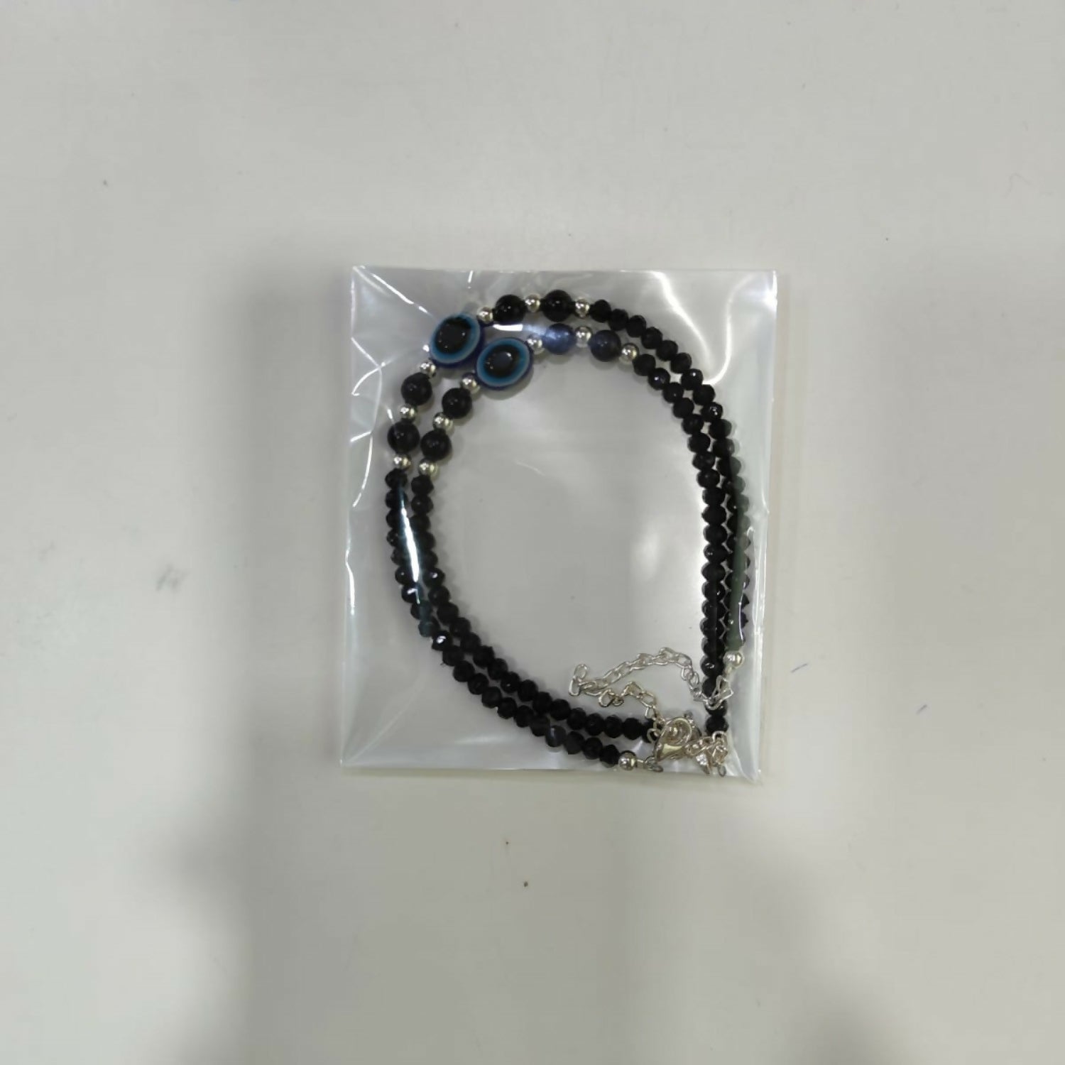 Lifestyle shot of the black evil eye anklet pair for women.
