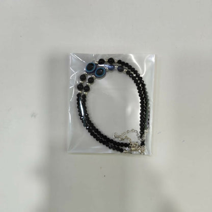 Lifestyle shot of the black evil eye anklet pair for women.