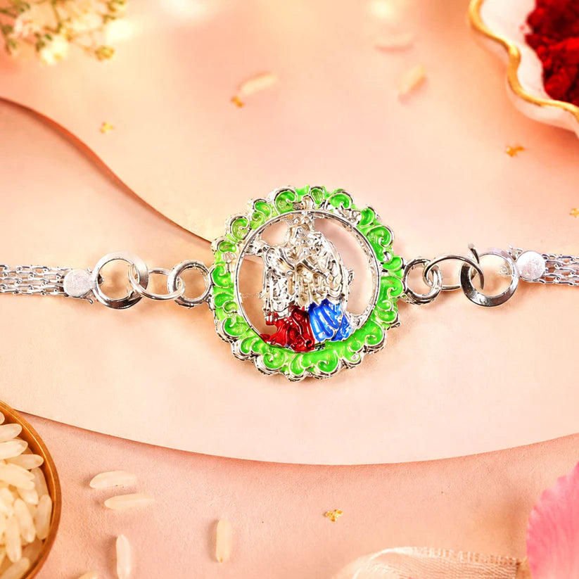Silver Chain Rakhi with Radha Krishna motif and green enamel border.