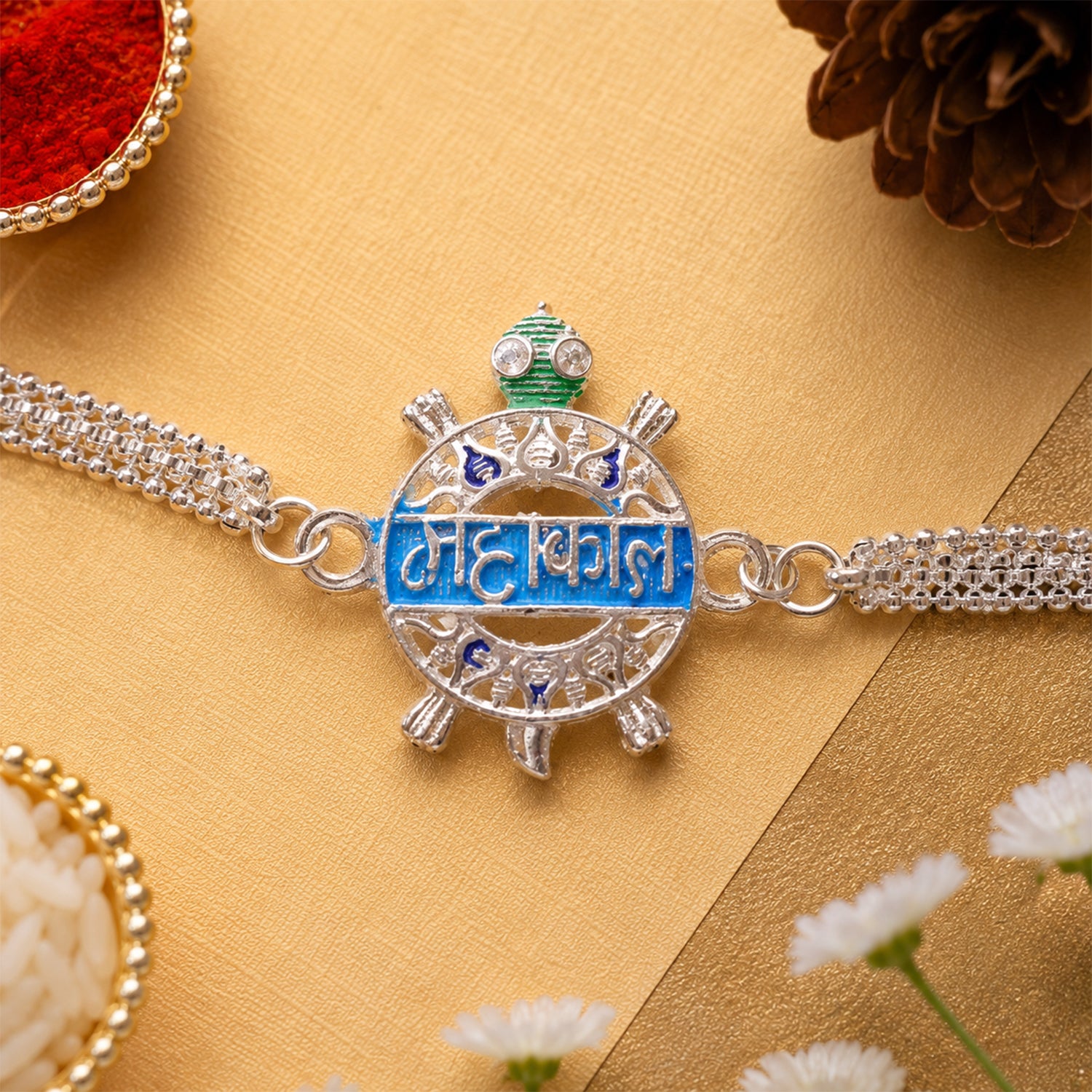 Close-up of Mahakal text charm on a designer chain Rakhi for brother.