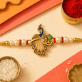 Shop Peacock Design Rakhi with Pearl Beads & Golden Detailing