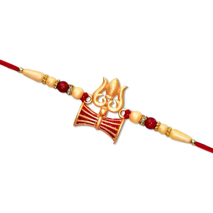 A gold Trishul and Damaru rakhi with red and cream beads on a red thread, isolated on a white background.