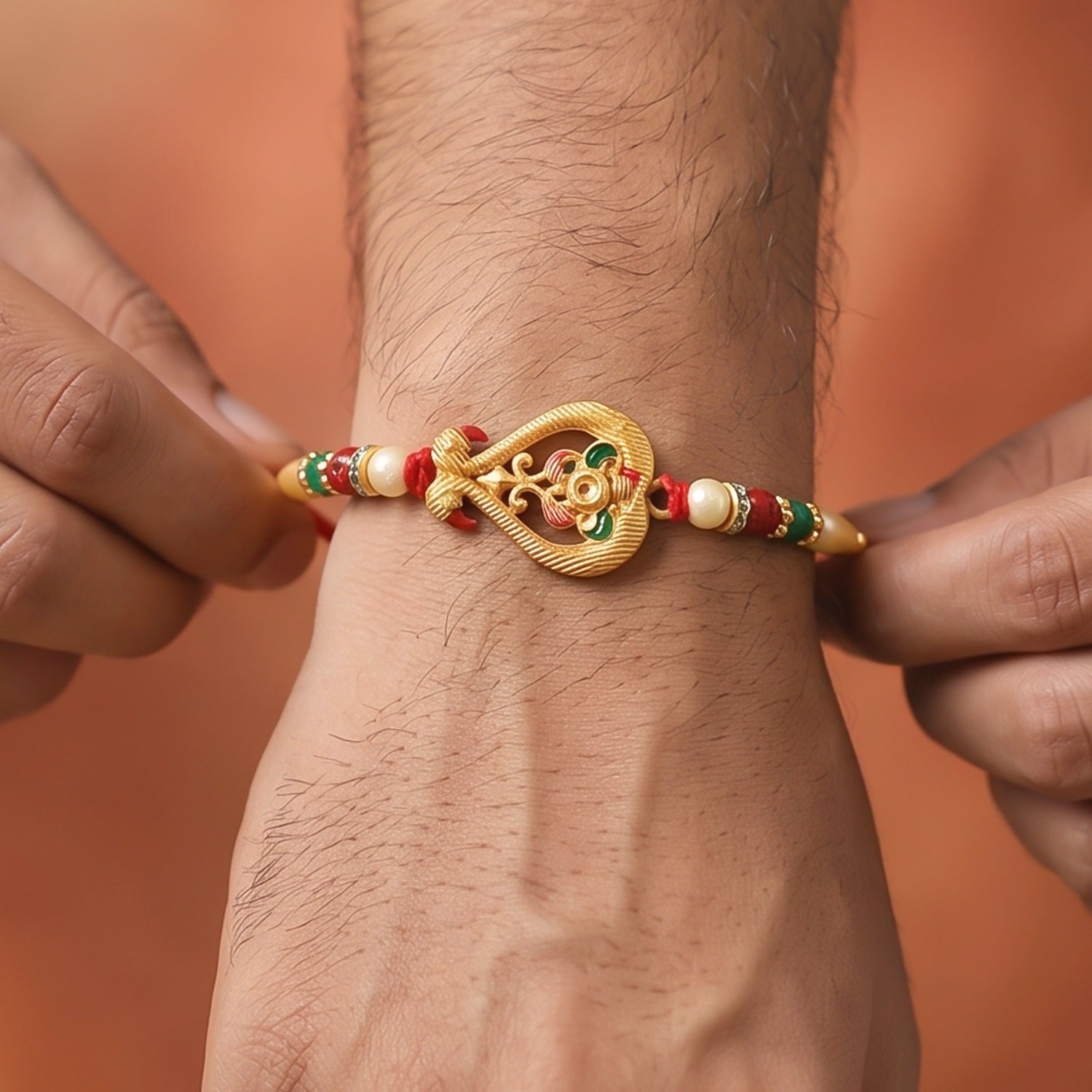 A person's hands adjusting a red thread bracelet with a gold-colored, ornate charm and colorful beads on their wrist.