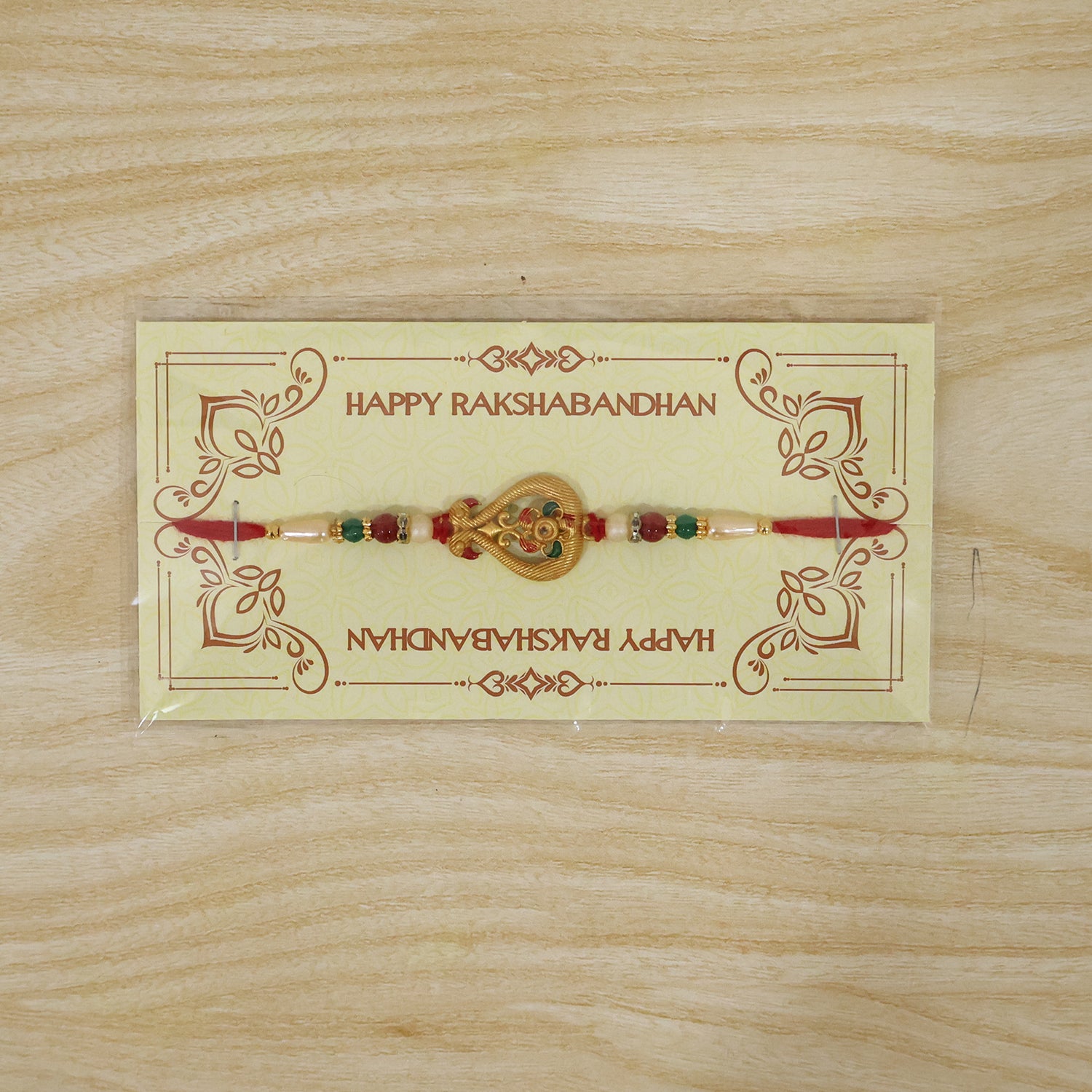 A red thread bracelet with a gold-colored, intricate charm and colorful beads, displayed on a