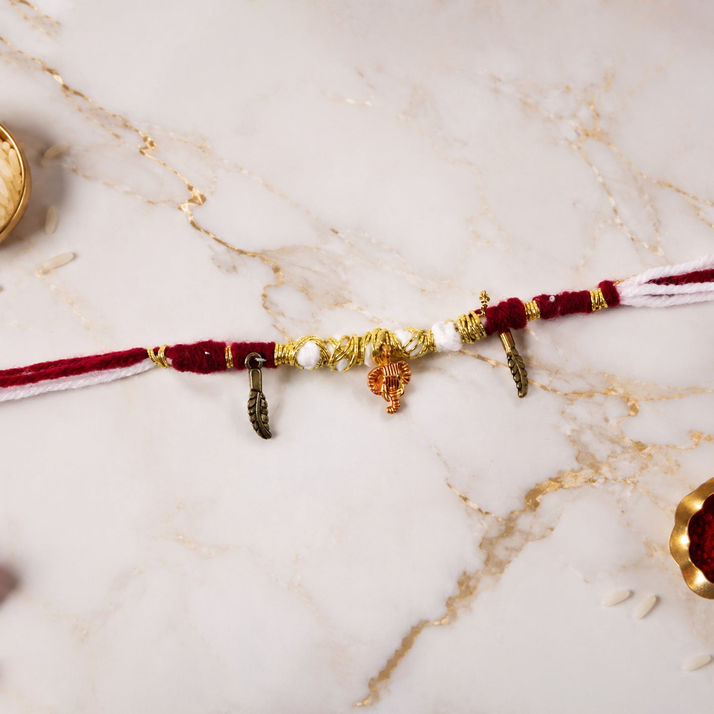 Close-up of Ganesh & Feather Charm on Thread Rakhi