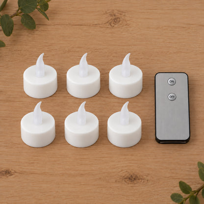 Six white LED flameless candles with clear plastic flames and a gray remote control on a light wooden surface.