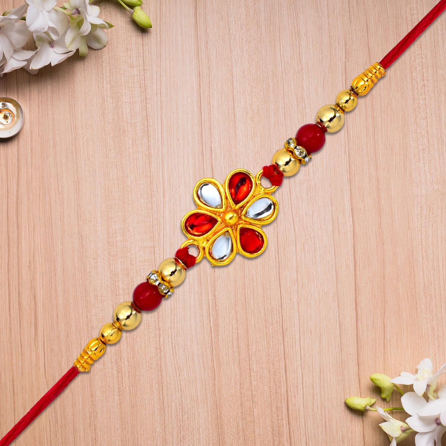 Elegant red and white beaded rakhi with teardrop kundan floral centerpiece