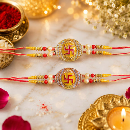 Two gold and rose gold Swastik bracelets with red and yellow threads lie on a white marble surface with scattered rice and