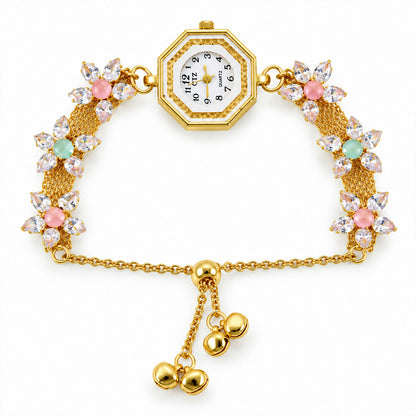 The gold-tone bracelet watch with an octagonal dial, crystal flowers, and hanging bell charms is centered on a white