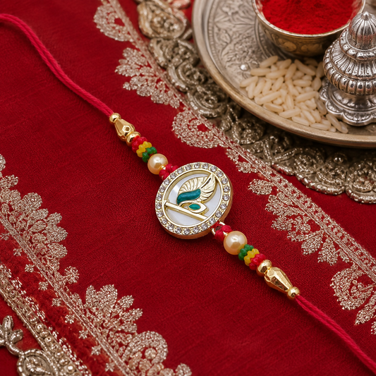 A gold-plated peacock feather design with American diamonds and pearls on a red thread, resting on a red embroidered cloth.