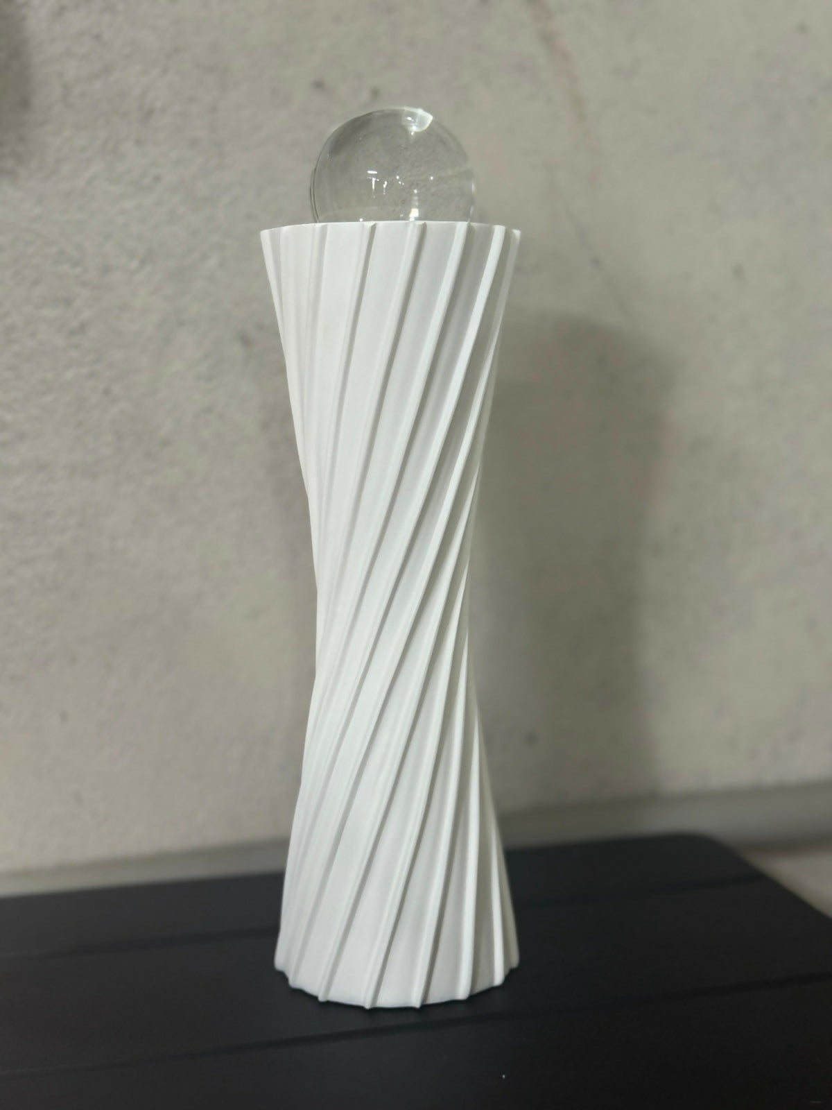 Modern white twisted resin showpiece with clear glass orb on tabletop