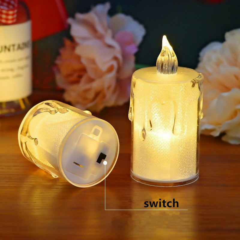 One glowing and one unlit clear plastic LED candle on a wooden surface, highlighting the power switch on the bottom of the