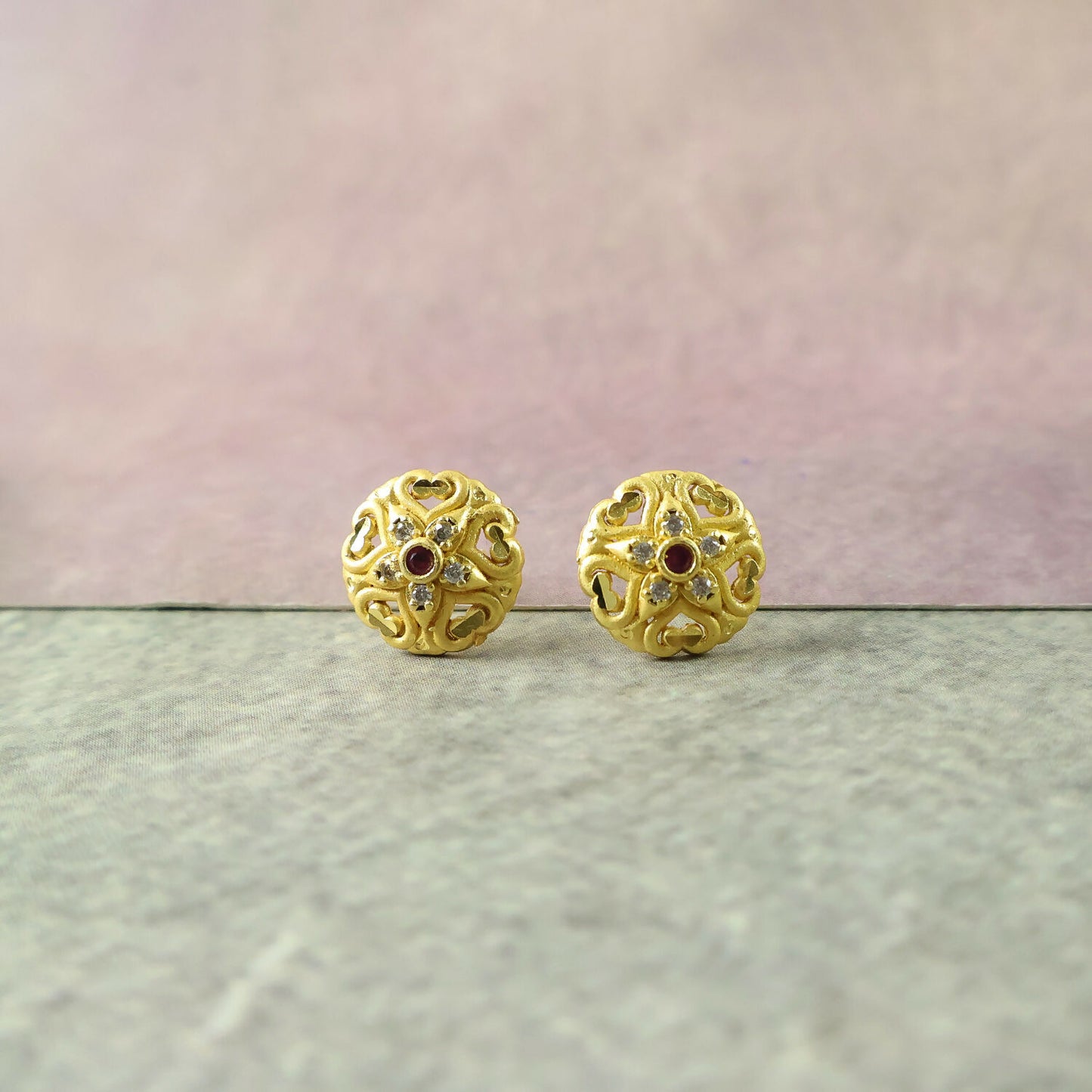 Pair of traditional gold stud earrings with floral motifs and shimmering stones