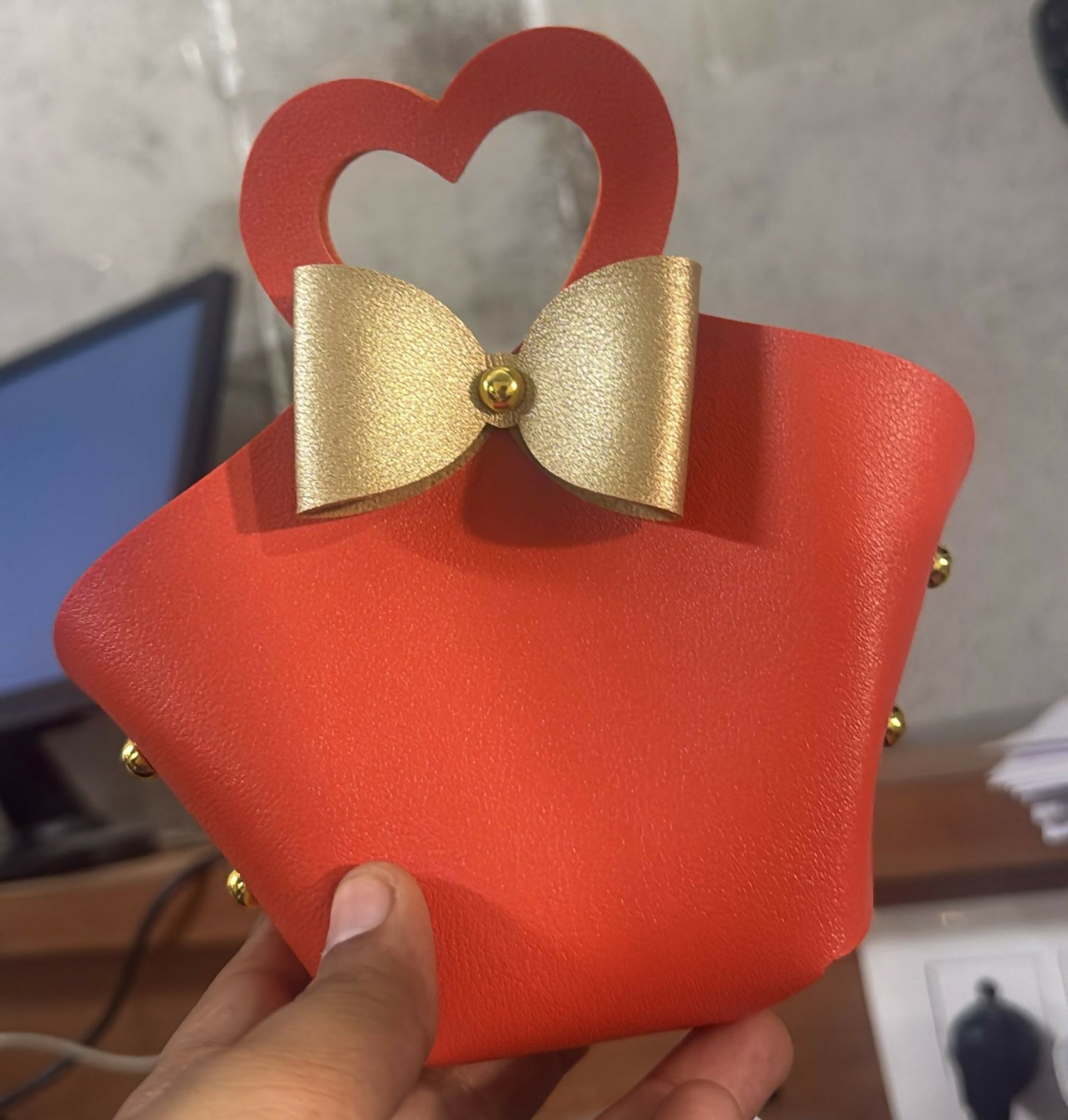 Close-up of orange mini handbag with heart-shaped handle and bow