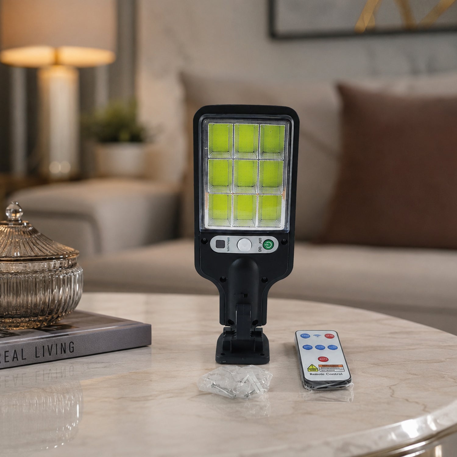 The black solar LED street light and its remote control are displayed on a marble table in a living room setting.