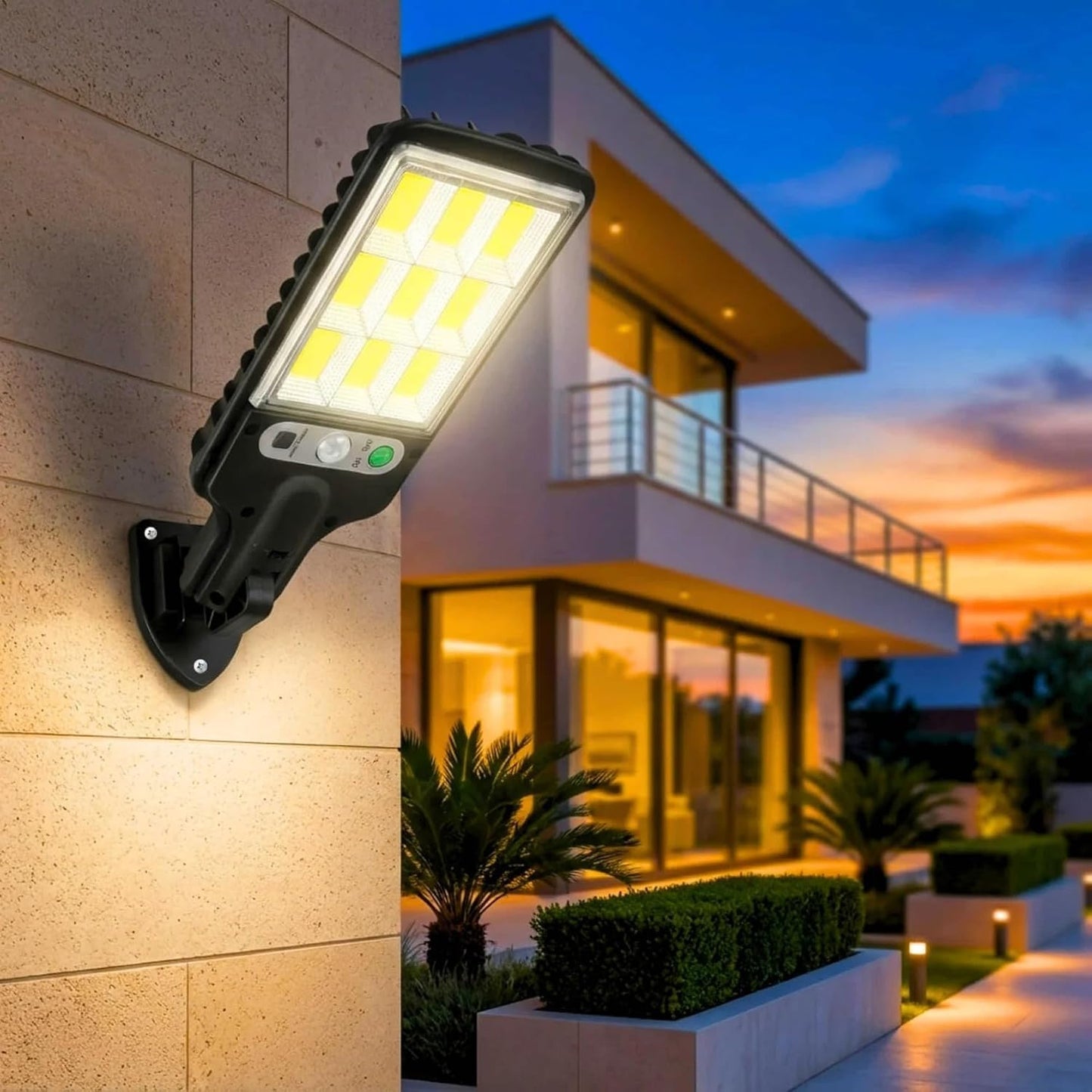 A black solar LED street light with a motion sensor is mounted on a light-colored brick wall, illuminating a modern house