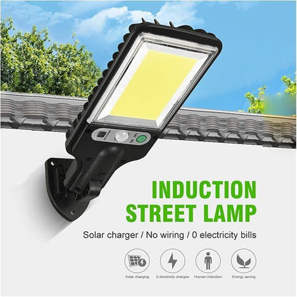 A black solar LED street light is mounted on a white wall with a tiled roof, displaying text about its solar charging and