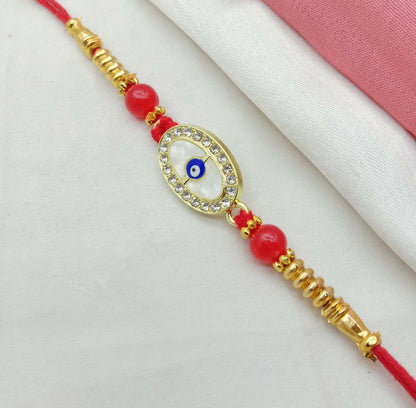 A close-up of a red thread bracelet shows a golden oval evil eye charm with white stones, flanked by red beads and golden