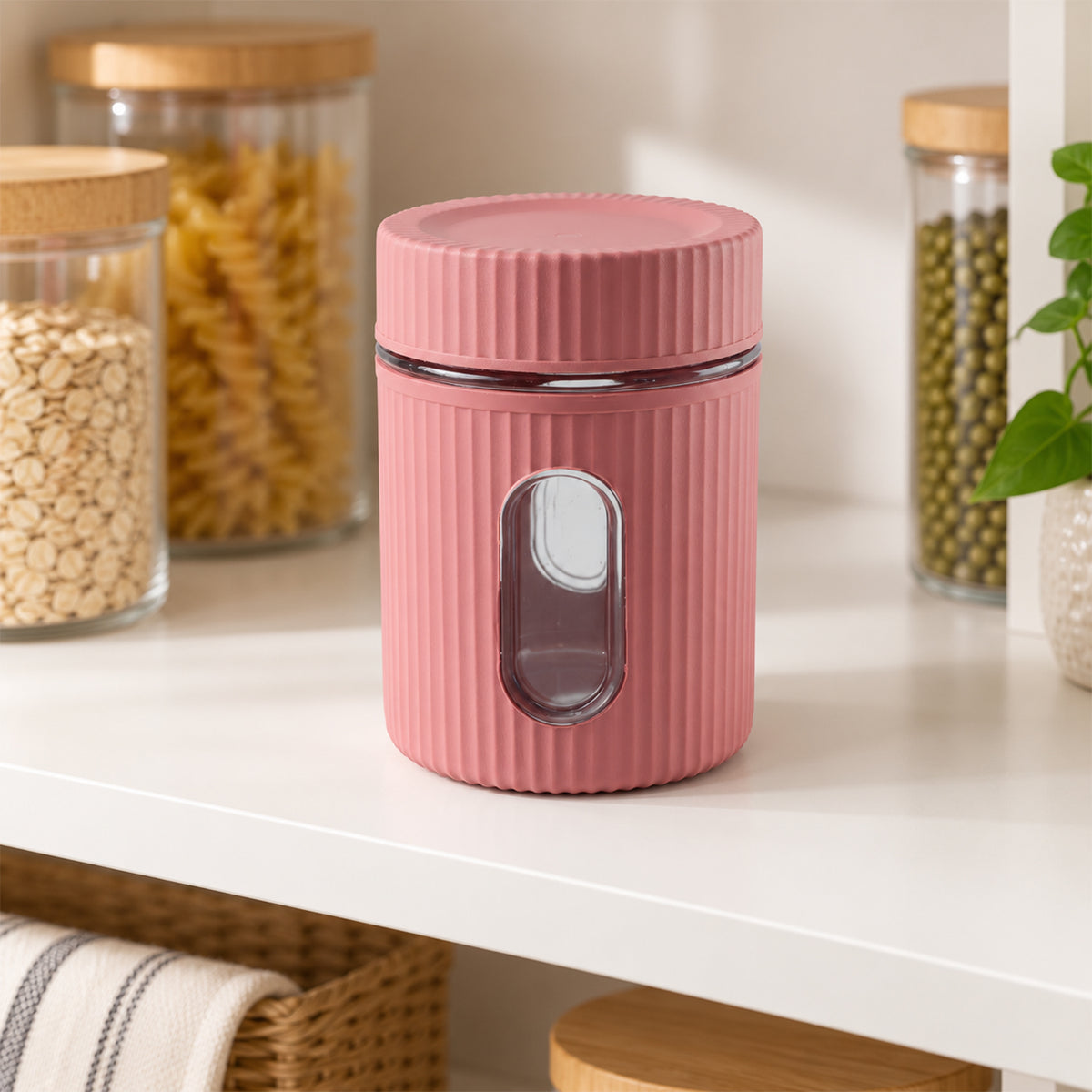 A pink ribbed storage jar with a clear window sits empty on a white shelf, surrounded by other food containers.